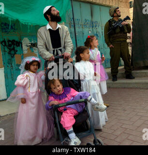 Rechtsgerichteten israelischen Siedlern und einem israelischen Soldaten sehen Sie eine Parade für die jüdische Feiertag Purim in Hebron, West Bank, 14. März 2006. Israelische Soldaten überfallen einen palästinensischen Gefängnis in Jericho aus gewalttätigen Demonstrationen und der Entführung von Ausländern im Westjordanland und im Gazastreifen. (UPI Foto/Debbie Hill) Stockfoto