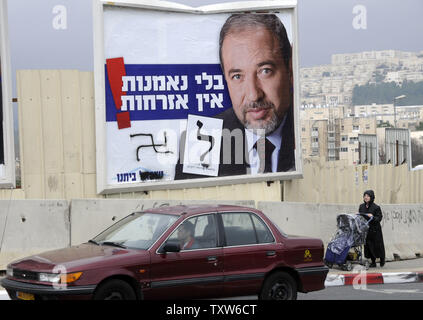 Israelis Pass eine Kampagne Plakatwand in Jerusalem, Vandalismus mit Nazi Hakenkreuze, der Israelischen nationalistischen Rechten Führer Avigdor Lieberman, Leiter der Yisrael Beitenu Partei, 1. Februar 2009. Lieberman ist für seine faschistische und extremistische Haltung bekannt. Jüngste Umfragen zeigen seine Yisrael Beitenu Partei im dritten Platz bei den bevorstehenden Wahlen in Israel, die am 10. Februar. (UPI Foto/Debbie Hill) Stockfoto