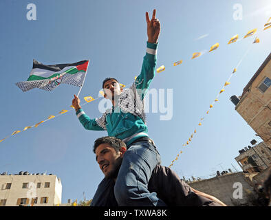 Eine palästinensische blinkt der Sieg unterzeichnen und Wellen eine Fatah Flagge auf der Kundgebung am feiern den 46. Jahrestag der Fatah-bewegung in Ramallah, West Bank, 3. Januar 2011. UPI/Debbie Hill Stockfoto