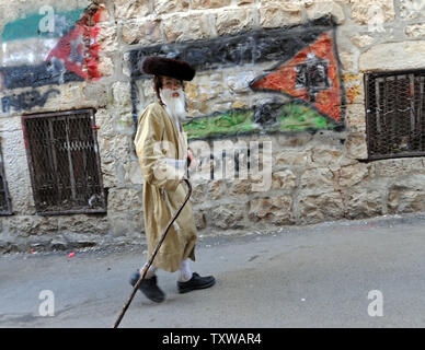 Ein Ultra-orthodoxen jüdischen Jungen gekleidet wie ein alter Mann Spaziergänge durch Graffiti der palästinensischen Flagge an Purim in der Mea Shearim in Jerusalem, 21. März 2011. Der jüdische Feiertag Purim feiert die Rettung der Juden aus Völkermord im alten Persien, wie im Buch Esther erzählt. UPI/Debbie Hill Stockfoto
