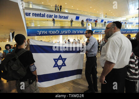 Rechten Israelis halten Sie, um israelische Fahnen, während Polizei verhaften Linke Aktivist Holding pro-palästinensischen Slogans am Flughafen Ben Gurion in der Nähe von Tel Aviv am 15. April 2012. Hunderte von Israelischen Polizei, viele überdachte wurden am Flughafen die Ankunft von pro-palästinensischen Aktivisten, die an einer 'Willkommen in Palästina" Fliegen zu blockieren - in eingesetzt. Gelobte Israel Eintrag von Aktivisten zu verhindern, warnen ausländische Fluggesellschaften sie gezwungen wäre, die Rechnung für die sofortige der Aktivisten kehren nach Hause zu Fuß. UPI/Debbie Hill Stockfoto