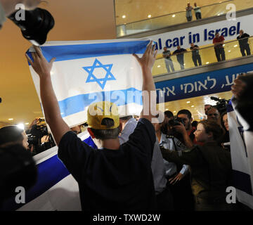 Rechten Israelis halten Sie, um israelische Fahnen, während Polizei verhaften Linke Aktivist Holding pro-palästinensischen Slogans am Flughafen Ben Gurion in der Nähe von Tel Aviv am 15. April 2012. Hunderte von Israelischen Polizei, viele überdachte wurden am Flughafen die Ankunft von pro-palästinensischen Aktivisten, die an einer 'Willkommen in Palästina" Fliegen zu blockieren - in eingesetzt. Gelobte Israel Eintrag von Aktivisten zu verhindern, warnen ausländische Fluggesellschaften sie gezwungen wäre, die Rechnung für die sofortige der Aktivisten kehren nach Hause zu Fuß. UPI/Debbie Hill Stockfoto