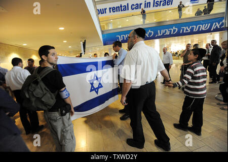 Rechten Israelis halten Sie, um israelische Fahnen, während Polizei verhaften Linke Aktivist Holding pro-palästinensischen Slogans am Flughafen Ben Gurion in der Nähe von Tel Aviv am 15. April 2012. Hunderte von Israelischen Polizei, viele überdachte wurden am Flughafen die Ankunft von pro-palästinensischen Aktivisten, die an einer 'Willkommen in Palästina" Fliegen zu blockieren - in eingesetzt. Gelobte Israel Eintrag von Aktivisten zu verhindern, warnen ausländische Fluggesellschaften sie gezwungen wäre, die Rechnung für die sofortige der Aktivisten kehren nach Hause zu Fuß. UPI/Debbie Hill Stockfoto