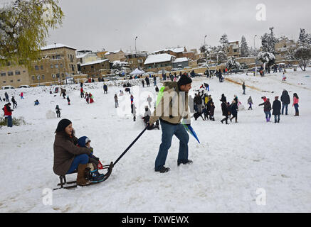 Ein israelischer zieht seine Familie auf einem Schlitten im Sacher Park im Zentrum von Jerusalem, Israel, 10. Januar 2013. Jerusalem zum Stillstand kam, schließen Schulen und wichtigen Autobahnen, wie acht Zoll Schnee den Heiligen gedreht Stadt weiß in die größte Schneefall seit 1992. UPI/Debbie Hill. Stockfoto