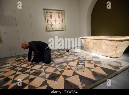 Ein Arbeiter bereitet einen Mosaikboden in der Nähe einer Badewanne aus Stein von der heißen Badewanne Haus des Königs Palast des Herodes an Cypros ausgegraben, Teil einer Ausstellung unter dem Titel "Herodes der Große: Des Königs letzte Reise", in dem Israel Museum, Jerusalem, Israel, 12. Februar 2013. Die Ausstellung beschäftigt sich mit 40 Jahren die archäologischen Ausgrabungen von das Leben und das Vermächtnis von König Herodes, der als der größte Baumeister in der menschlichen Geschichte erinnert wird. Er ist für aufwändige Paläste, Festungen, wie Masada bekannt, und der Wiederaufbau des Tempels in Jerusalem während der römischen Epoche. Herodes regierte seit über 30 Jahren in, was jetzt k Stockfoto