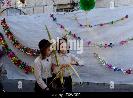 Ultra-orthodoxe jüdische Jungen tragen lulav, ein Datum palm Zweig, vor Dekorationen für die Sukkot Festival, oder Fest der Laubhütten, Jerusalem, Israel, 16. September 2013. Die Sukkot Urlaub erinnert an die 40 Jahre, die die Söhne Israel in der Wüste nach dem Auszug aus Ägypten wanderte. Die einwöchigen Urlaub beginnt bei Sonnenuntergang Mittwoch. UPI/Debbie Hill Stockfoto