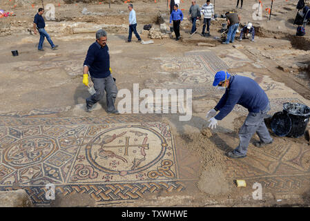 Arbeiter von der Israel Antiquities Authority die Arbeit an einem großen bunten Mosaik mit alten Inschriften, die in die Überreste eines großen byzantinischen Kirche gefunden wurde, ca. 1.500 Jahre alt, bei Ausgrabungen von der Israel Antiquities Authority in Moshav Aluma, im Süden Israels, 22. Januar 2014. Das Mosaik ist ein Christogram, mit einem Kreuz - wie Abbildung, dass symbolisiert Jesus Christus, und Vögel Anheben das Symbol in den Himmel. Die griechischen Buchstaben Alpha und Omega sind auch in der Mosaik gefunden. Die Kirche ist 22 Meter lang und 12 Meter breit und war Teil eines großen und bedeutenden Byzantinischen settlem Stockfoto