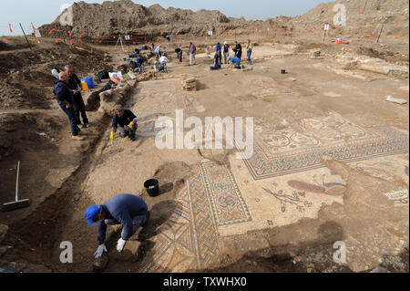 Arbeiter von der Israel Antiquities Authority die Arbeit an einem großen bunten Mosaik mit alten Inschriften, die in die Überreste eines großen byzantinischen Kirche gefunden wurde, ca. 1.500 Jahre alt, bei Ausgrabungen von der Israel Antiquities Authority in Moshav Aluma, im Süden Israels, 22. Januar 2014. Das Mosaik ist ein Christogram, mit einem Kreuz - wie Abbildung, dass symbolisiert Jesus Christus, und Vögel Anheben das Symbol in den Himmel. Die griechischen Buchstaben Alpha und Omega sind auch in der Mosaik gefunden. Die Kirche ist 22 Meter lang und 12 Meter breit und war Teil eines großen und bedeutenden Byzantinischen settlem Stockfoto