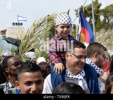 Eine palästinensische christliche Junge sitzt auf den Schultern seines Vaters während der jährlichen Palmsonntag Prozession auf dem Ölberg in Jerusalem, Israel, 13. April 2014. Lokale und internationale Christen ging den Pfad, wo Jesus Christus ein Esel in Jerusalem vor mehr als 2.000 Jahren ritt. Der Palmsonntag ist der Beginn der Heiligen Woche. UPI/Debbie Hill Stockfoto
