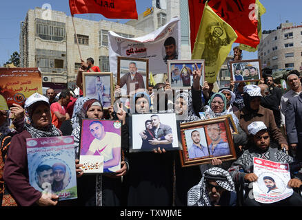 Palästinenser halten Fotos von Familienmitgliedern, die in israelischen Gefangenen während eines Protestes auf palästinensischer Gefangener in Ramallah, West Bank, 17. April 2014 statt. Nach Angaben von palästinensischen Menschenrechtsorganisationen gibt es mehr als 5.000 Palästinenser in israelischen Gefängnissen. Palästinensischen Beamten fordern, dass Israel die vierte Gruppe von Gefangenen, um die Friedensgespräche über den 29. April Frist zu verlängern. UPI/Debbie Hill Stockfoto
