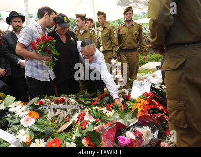 Stuart Steinberg (R), aus Kalifornien, legt einen Stein auf die Blumenbewachsenen Grab seiner Erschlagenen Sohn, amerikanisch-israelische Soldat Max Steinberg, 24, nach seiner Beerdigung in den Soldatenfriedhof am Mt. Herzl in Jerusalem, Israel, 23. Juli 2014. Steinberg, ein Eingeborener von Los Angeles, Kalifornien, wanderten nach Israel ein und trug in der israelischen Streitkräfte im Jahr 2012, wo er als Scharfschütze in der Elite Golani Brigade serviert. Er war unter den 13 Soldaten durch palästinensische Extremisten im Gaza-streifen am Sonntag getötet. 29 israelische Soldaten getötet wurden, da die Armee einen Einfall ich gestartet Stockfoto