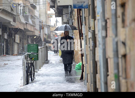 Eine ultra-orthodoxe Juden Gespräche am Mobiltelefon beim Wandern im Schnee und Regen während ein Wintersturm in Jerusalem, Israel, 8. Januar 2015. Ein schwerer Sturm trifft den Nahen Osten, während nur 5 cm oder 1 cm Schnee in Jerusalem fiel. UPI/Debbie Hill Stockfoto