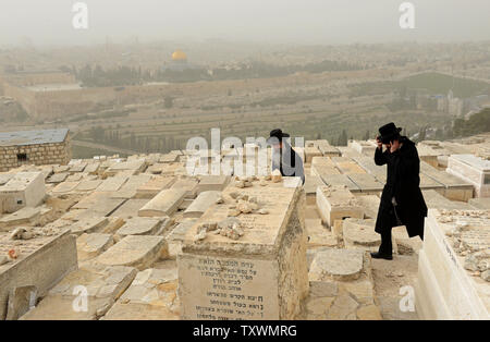 Ultra-orthodoxe Juden weg, während ein Sandsturm auf dem Friedhof auf dem Ölberg in Jerusalem, mit Blick auf den Felsendom in der Altstadt von Jerusalem, 11. Februar 2015. Die israelische Umweltschutz Ministerium berichtet, dass der Sandsturm durch das Land fegt verursacht hat die Luftverschmutzung die höchsten in den letzten fünf Jahren zu werden. Foto von Debbie Hill/UPI Stockfoto