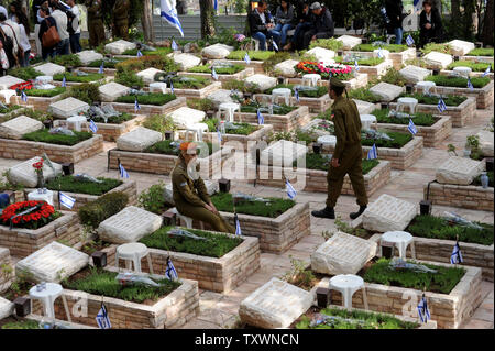 Ein israelischer Soldat sitzt durch die Gräber der gefallenen Soldaten am Memorial Day in der Mt. Herzl Soldatenfriedhof in Jerusalem, Israel, 22. April 2015. Tausende von Israelis besucht Friedhöfe im gesamten Land zu trauern um den 23,320 in Israels Schlachten gefallenen seit 1948. Foto von Debbie Hill/UPI Stockfoto