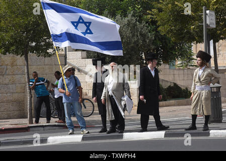 Ein israelischer Mann hält eine große israelische Flagge neben ultra-orthodoxe Juden in der Nähe von der Stelle von einem Stechenden von einem palästinensischen Jugend gegen zwei religiöse Juden außerhalb der Mauern der Altstadt von Jerusalem, 10. Oktober 2015. Ein Palästinenser erschossen wurde und auf der Szene durch die israelische Polizei getötet, nachdem er verwundet zwei jüdische Männer in einem stechenden Angriff. Es ist der neueste in einer Welle von messerstechereien gegen Zivilisten und Soldaten in Israel und der West Bank diese letzte Woche. Foto von Debbie Hill/UPI Stockfoto