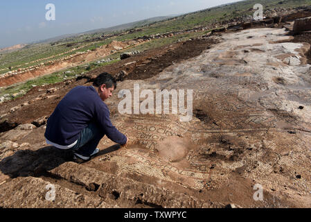 Ein Mann schaut auf eine Antike Mosaik mit einer Inschrift auf dem Boden einer 1,5000 Jahr alten byzantinischen Kloster von 500 CE, ausgegraben, die von den israelischen Antiquities Authority in Rosh Ha-Ayin, in der Nähe von Tel Aviv, Israel, 30. Dezember 2015. Das Kloster wurde entdeckt, weil Archäologen müssen alle neuen Baustellen und eine neue Nachbarschaft wird in der Region prüfen. Das Kloster eine Kirche untergebracht, eine Ölpresse, Wohnquartiere für ca. 30 Personen und Stallungen. Es ist eine griechische Inschrift in bunten Mosaiken, die lautet: "Dieser Ort unter Theodosius der Priester gebaut wurde. Der Friede sei mit dir, wenn yo Stockfoto