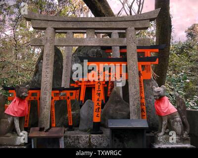 Kleine rote Torii Tor und Fox Statuen in Fushimi Inari Taisha Shrine, es ist das beliebteste Wahrzeichen von Kyoto, Japan. Stockfoto