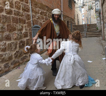 Eine israelische Tänze mit seinen Kindern zu Der jüdische Feiertag Purim in Jerusalem, Israel, 25. März 2016 feiern. Purim ist ein freudiger Urlaub, feiert das Heil der Juden von Völkermord im alten Persien, wie sie im Buch Esther erzählt. Foto von Debbie Hill/UPI Stockfoto