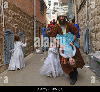 Eine israelische Tänze mit seiner Tochter der jüdische Feiertag Purim in Jerusalem, Israel, 25. März 2016 zu feiern. Purim ist ein freudiger Urlaub, feiert das Heil der Juden von Völkermord im alten Persien, wie sie im Buch Esther erzählt. Foto von Debbie Hill/UPI Stockfoto