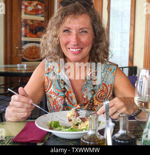 Schön, gesund und zufrieden lächelnd reife Frau essen Bio essen im Restaurant Stockfoto