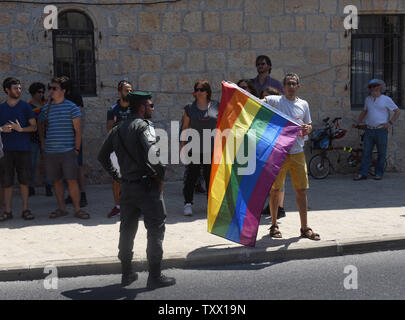 Eine Grenze der Polizei steht vor einem israelischen Holding ein Regenbogen Flagge während eines Protestes gegen Diskriminierung von LGBT-Personen und den Ausschluss von homosexuellen Männern von der Leihmutterschaft Gesetz, in der vergangenen Woche von der Regierung verabschiedet, in der Nähe der israelischen Premierminister Benjamin Netanjahu in Jerusalem, Israel, 22. Juli 2018. Hunderte von Mitarbeitern erlaubt, ihre Mitarbeiter heute ohne Strafe zur Unterstützung der Rechte von Homosexuellen zu streiken. Die Demonstranten riefen Parolen gegen Premierminister Netanyahu, sagte, daß er die Leihmutterschaft, die homosexuelle Männer enthalten unterstützt, aber gegen ihn gestimmt. Foto von Debbie Hill/UPI Stockfoto