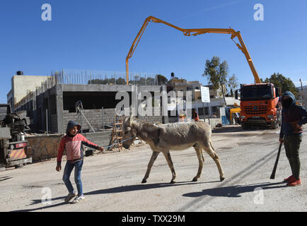 Ein palästinensischer Junge Spaziergänge sein Esel vorbei an der Baustelle der Schule des Mädchens in Al-Jabba, in der Nähe von Bethlehem, West Bank, die von der USAid, US-Behörde für Internationale Entwicklung, 23. Januar 2019 finanziert wird. Die $ 1,4 Millionen Dollar Projekt wird Ende Januar beendet werden, da die Verwaltung der US-Präsident Donald Trump Stop wird der Finanzierung palästinensischer Projekte und auch wegen dem palästinensischen Ministerpräsidenten Rami Hamdallah erklärt hat, dass die Palästinensische Autonomiebehörde nicht mehr akzeptieren Finanzierung aus Amerika. Die Schule wird für die 250 Studentinnen, die die Sch besuchen unbrauchbar werden. Stockfoto