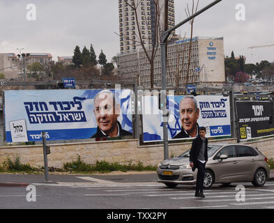 Ein Mann kreuzt die Straße vor Wahlkampf Plakate für den israelischen Premierminister Benjamin Netanjahu in Jerusalem, 1. April 2019. Über 500 gefälschte social media Konten haben, über den ein Watchdog Gruppe ausgesetzt worden, die Förderung Netanjahus Wiederwahl. Die gefälschte Konten haben 2,5 Millionen Treffer. Israelis Abstimmung am 9. April. Foto von Debbie Hill/UPI Stockfoto