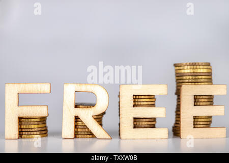 Bars von Münzen auf einem weißen Tisch gestapelt. Kostenlose Schriftzug mit Holz Buchstaben auf Münzen. Weißer Hintergrund. Stockfoto