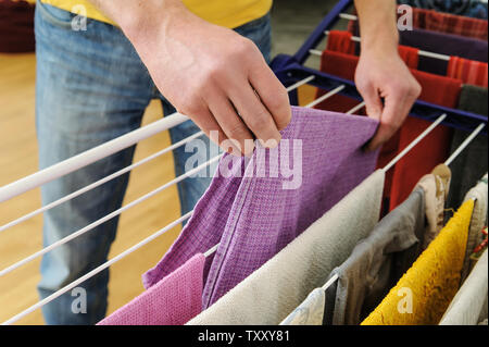 Ein Mann nimmt Handtücher von Wäscheständer Kleidung. Stockfoto