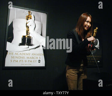 Ein Besucher stellt mit einem Oscar statuette als Teil der 50 Oscar Statuetten auf Ausstellung bei den Oscars in Hollywood" in Los Angeles, Kalifornien am 27. Februar 2006. Die Ausstellung zeigt Fotografien aus früheren Academy Awards, den Oscar gewonnen von Clark Gable für seine Rolle in "Mit Dem Wind" und die 50 Oscars, die Gewinner am 78. jährliche Oscar-Verleihung in Hollywood am 5. März vorgelegt werden soll. (UPI Foto/Jim Ruymen) Stockfoto