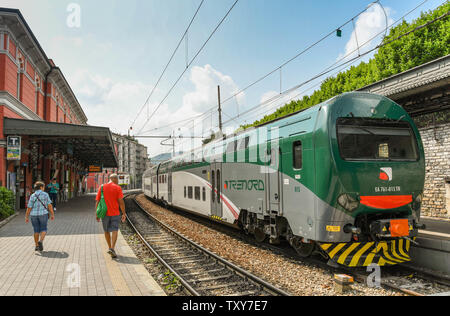 COMO, ITALIEN - Juni 2019: Zwei Menschen zu Fuß auf der Plattform in der Innenstadt von North Lake Como, eine moderne elektrische Zug ist auf einer Plattform Stockfoto