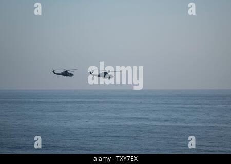 Militärische Hubschrauber fliegen im Tandem über dem Ozean Stockfoto