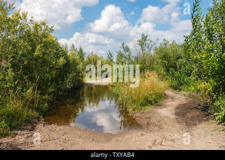 Gebrochen, unbefestigte Straße mit Pfützen in der Wald in der russischen Sibirien im Sommer Tag Stockfoto