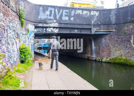 Hackney, East London, England, UK - April 2019: Mann gehen der Hund entlang der Regent's Canal in der Nähe von Broadway, East London Stockfoto