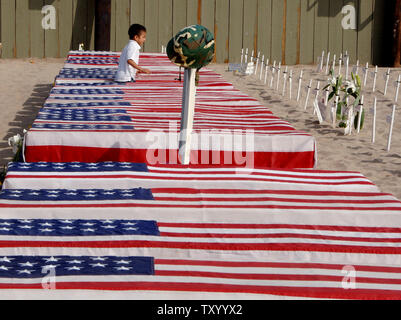 Ein Junge dart Vergangenheit Flagge - drapierte Schatullen auf Anzeige an der Arlington West Memorial Projekt in Santa Monica, Kalifornien am 26. Mai 2007. Der Strand Memorial verfügt über tausende von Kreuzen als die 3.452 Soldaten, die im Irak gestorben sind. (UPI Foto/Jim Ruymen) Stockfoto