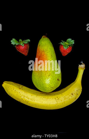 Lächelnd Obst Gesicht mit Erdbeere Augen auf schwarzem Hintergrund Stockfoto