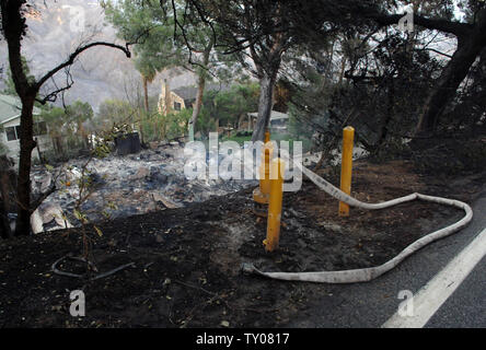 Ein löschschlauch schlummert, wie die verkohlten Überreste eines Hauses auf Corral Canyon Rd. in Malibu, Kalifornien wird dargestellt, nach einem sich schnell bewegenden wildfire, das von Santa Ana Winde getrieben durch die canyons Raste und über die Berge des prominenten Enklave früher Samstag, November 24, 2007, ausnehmen, mindestens 50 Millionen Dollar Wohnungen und zwingt so viel, wie 14.000 Bewohnern zu fliehen. (UPI Foto/Jim Ruymen) Stockfoto