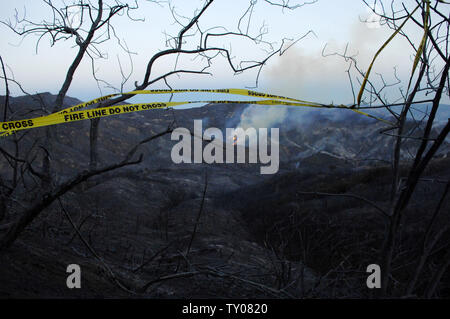 Fire line Tape bläst in wehenden Winde inmitten der verkohlten Überreste von Häusern auf Corral Canyon Rd. in Malibu, Kalifornien nach einem sich schnell bewegenden wildfire, das von Santa Ana Winde geschoben liefen durch die Schluchten und über die Berge des prominenten Enklave früher Samstag, November 24, 2007, ausnehmen, mindestens 50 Millionen Dollar Wohnungen und zwingt so viel, wie 14.000 Bewohnern zu fliehen. (UPI Foto/Jim Ruymen) Stockfoto