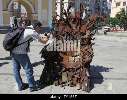 Kiew, Kiew, Ukraine. 25. Juni 2019. Ein Mann nimmt ein Bild von der Eiserne Thron, während der Präsentation auf dem Platz der Unabhängigkeit in Kiew, Ukraine. Die 600 kg Kunst Arbeiten von Armee freiwillige Denis Bushtets "Eiserne Thron des Ostens'' ist der Tank Stücke, Patrone, Gürtel, Fragmente von Raketen, Maschinengewehre, Granaten, Soldat, Flakons und andere militärische Artefakte, die auf der vorderen Linie mit Russland aufgenommen wurden - unterstützte Separatisten im Osten der Ukraine. Ein Prototyp eines berühmten Bügeleisen Thron von Spiel der Throne TV-Serie ist eine Erinnerung an einen blutigen Konflikt, der bereits rund 13.000 p getötet hat. Stockfoto