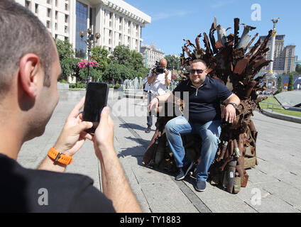 Kiew, Kiew, Ukraine. 25. Juni 2019. Ein Mann posiert für ein Foto, während in den Eisernen Thron sitzt, während der Präsentation auf dem Platz der Unabhängigkeit in Kiew, Ukraine. Die 600 kg Kunst Arbeiten von Armee freiwillige Denis Bushtets "Eiserne Thron des Ostens'' ist der Tank Stücke, Patrone, Gürtel, Fragmente von Raketen, Maschinengewehre, Granaten, Soldat, Flakons und andere militärische Artefakte, die auf der vorderen Linie mit Russland aufgenommen wurden - unterstützte Separatisten im Osten der Ukraine. Ein Prototyp eines berühmten Bügeleisen Thron von Spiel der Throne TV-Serie ist eine Erinnerung an ein blutiger Konflikt bereits kille Stockfoto