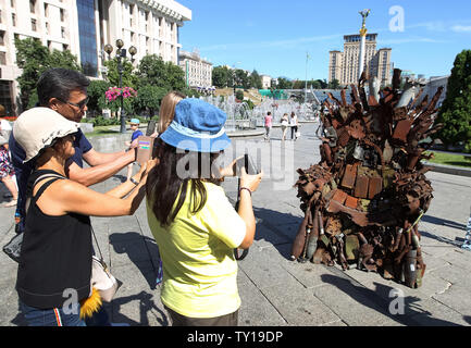 Kiew, Kiew, Ukraine. 25. Juni 2019. Touristen machen Fotos von den Eisernen Thron, während der Präsentation auf dem Platz der Unabhängigkeit in Kiew, Ukraine. Die 600 kg Kunst Arbeiten von Armee freiwillige Denis Bushtets "Eiserne Thron des Ostens'' ist der Tank Stücke, Patrone, Gürtel, Fragmente von Raketen, Maschinengewehre, Granaten, Soldat, Flakons und andere militärische Artefakte, die auf der vorderen Linie mit Russland aufgenommen wurden - unterstützte Separatisten im Osten der Ukraine. Ein Prototyp eines berühmten Bügeleisen Thron von Spiel der Throne TV-Serie ist eine Erinnerung an einen blutigen Konflikt, der bereits rund 13.000 pe getötet hat. Stockfoto