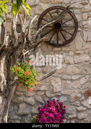 Rote Blumen in der künstlerischen Blumenarrangement mit Wagenrad Stockfoto