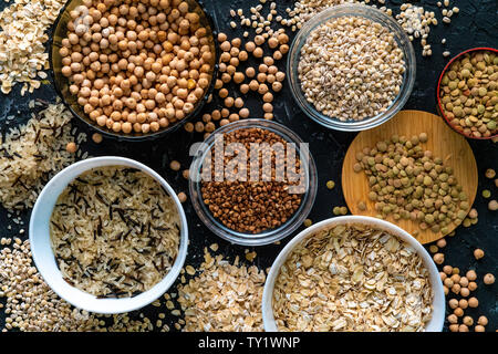 Auswahl von Roh ungekocht Getreide Körner in Glühbirnen mit Kichererbsen Linsen Hafer Reis buckwheats Stockfoto