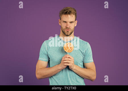 Geschmack der Kindheit. Man bärtige Erwachsene mag Lollipop. Sweet Tooth Konzept. Zucker schädlich für die Gesundheit. Kerl halten Lollipop candy violett unterlegt. Mann schöner macho Essen großen bunten süßen Lutscher. Stockfoto