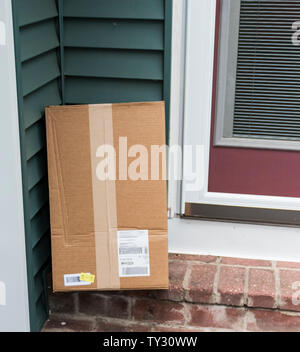 Ein Paket wird an die Seitentür eines Wohnhaus, nachdem er von einer Lieferung Unternehmen geliefert werden. Stockfoto