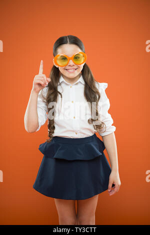 Lustige Idee. Kleines Mädchen in lustige Brille Zeigefinger auf orangem Hintergrund. Lustig kind Sonnenbrille tragen mit Farbfilter. Meine Augen gehen lustig. Stockfoto