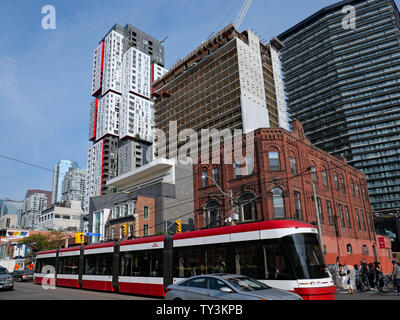 TORONTO - JUNI 2019: Eine bunte Mischung von Architektur in der Queen Street, das Hotel ist ein hohes, modernes Gebäude hinter kleinen Älteren. Stockfoto