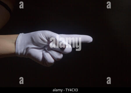 Geste. Hand in weißen Handschuh zeigen, isoliert auf Schwarz. Stockfoto