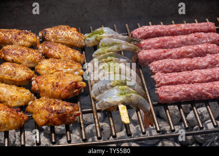 Gemischtes Sortiment von mariniertem Fleisch, Huhn und Garnelen Grillen auf heißen Kohlen auf einen Grill, einen Außenpool im Sommer Party, köstliche Mahlzeit Vorbereitung Stockfoto