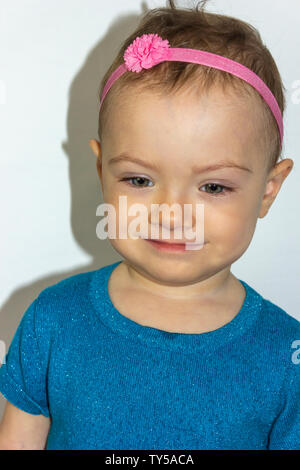 Sehr süße 20 Monate alten Baby Portrait. Schöne 1 Jahr altes Kleinkind Mädchen, natürlich posieren. Kleine Mädchen, das Tragen von niedlichen blauen Kleid und ein rosa Stirnband. Stockfoto